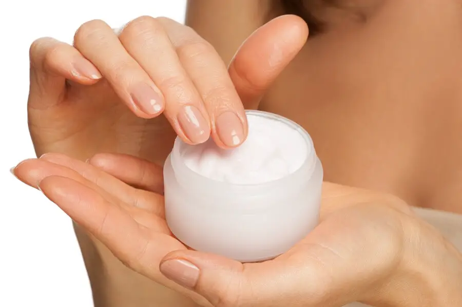 close up woman removing some cream out of a small container