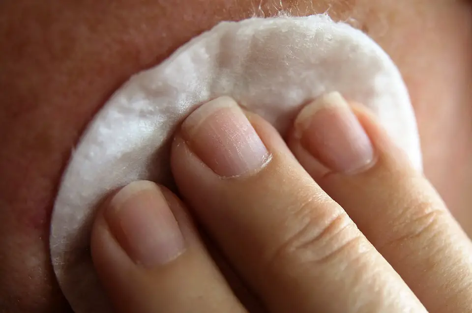 Person dabbing a cotton on skin